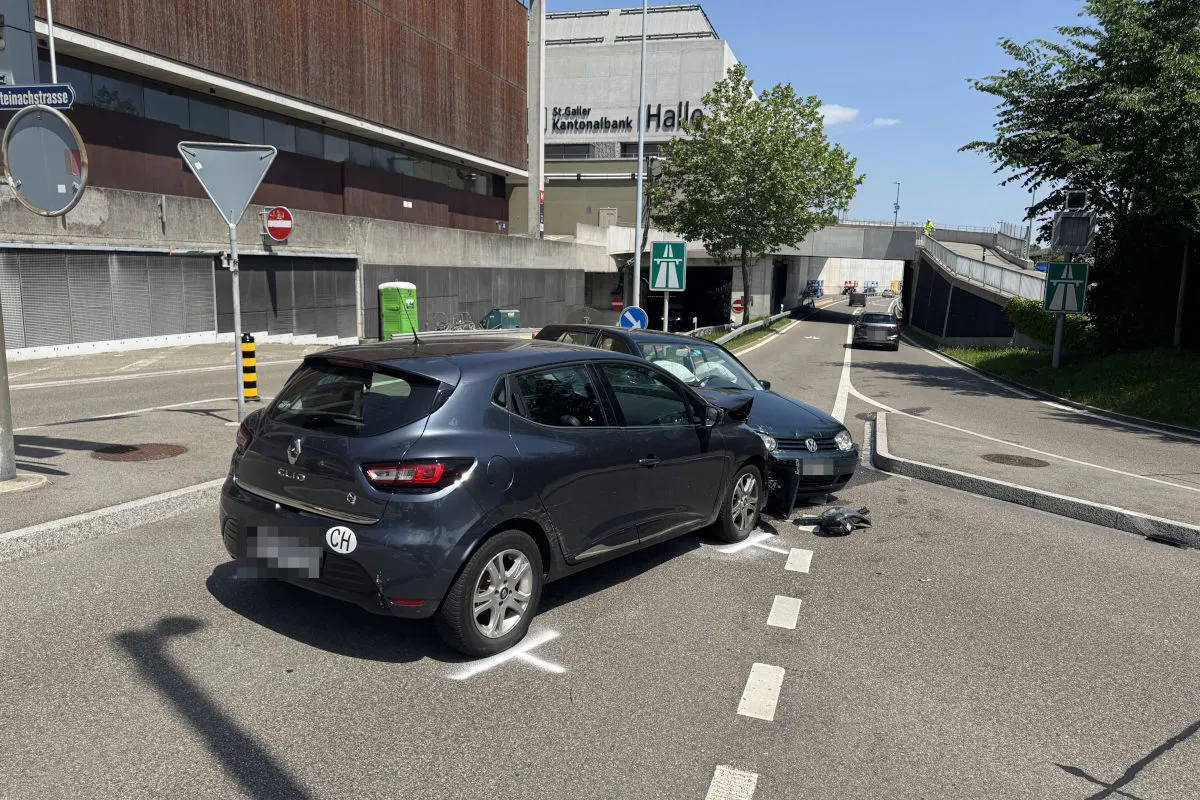 Ein Renault und ein VW stehen nach einem Unfall auf einer zweispurigen Straße vor einem Gebäude. Markierungen sind sichtbar.