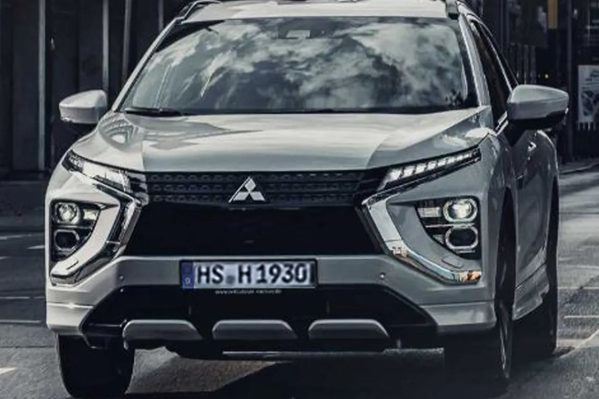 Ein weißer Mitsubishi SUV, fotografiert von vorne, fährt auf einer asphaltierten Straße. Das Kennzeichen ist gut sichtbar.