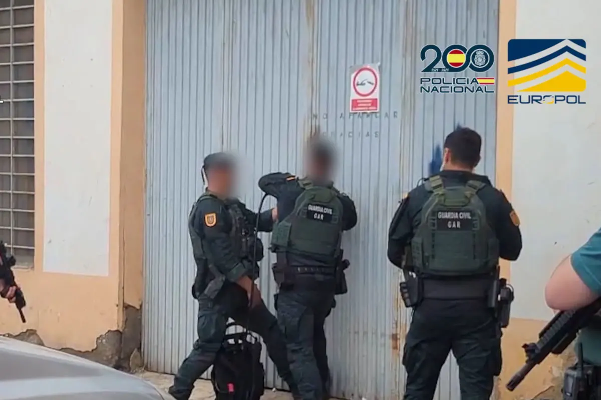 Mehrere Polizisten in Uniform haben sich vor einem metallischen Tor versammelt. Auf ihrem Rücken ist die Aufschrift 'Guardia Civil GAR' zu erkennen.