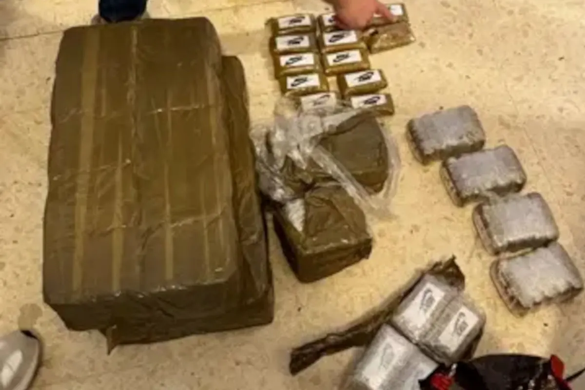 Auf dem Boden liegen mehrere Pakete, die in brauner Folie verpackt sind. Eine Person zeigt auf eines der kleineren Pakete.