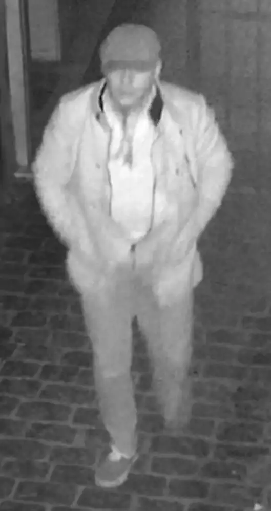 Eine unscharfe Schwarz-Weiß-Aufnahme zeigt eine Person mit Mütze und Jacke, aufgenommen von einer Überwachungskamera.