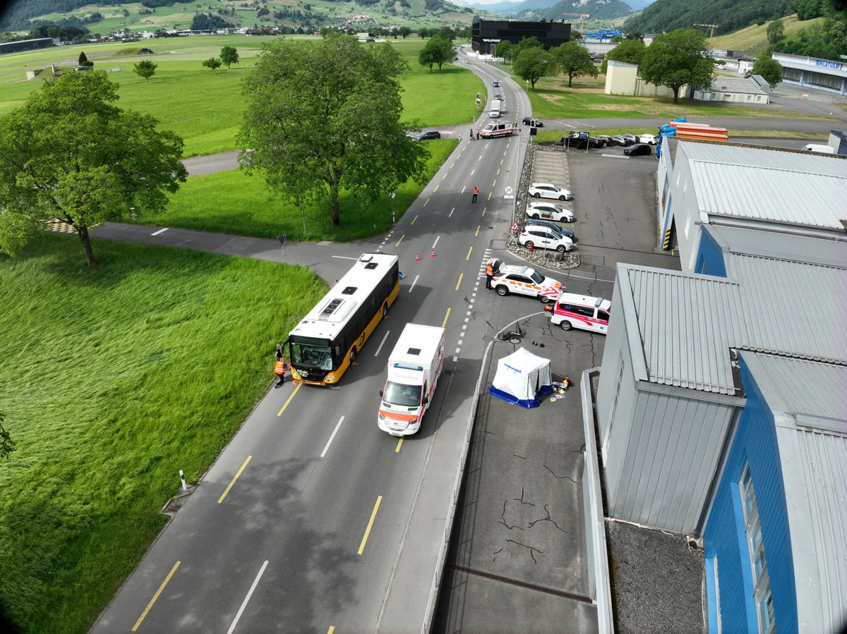 Ein Bus und ein Krankenwagen stehen auf einer Landstraße, flankiert von mehreren Polizeifahrzeugen. Ein Zelt ist am Straßenrand aufgestellt.