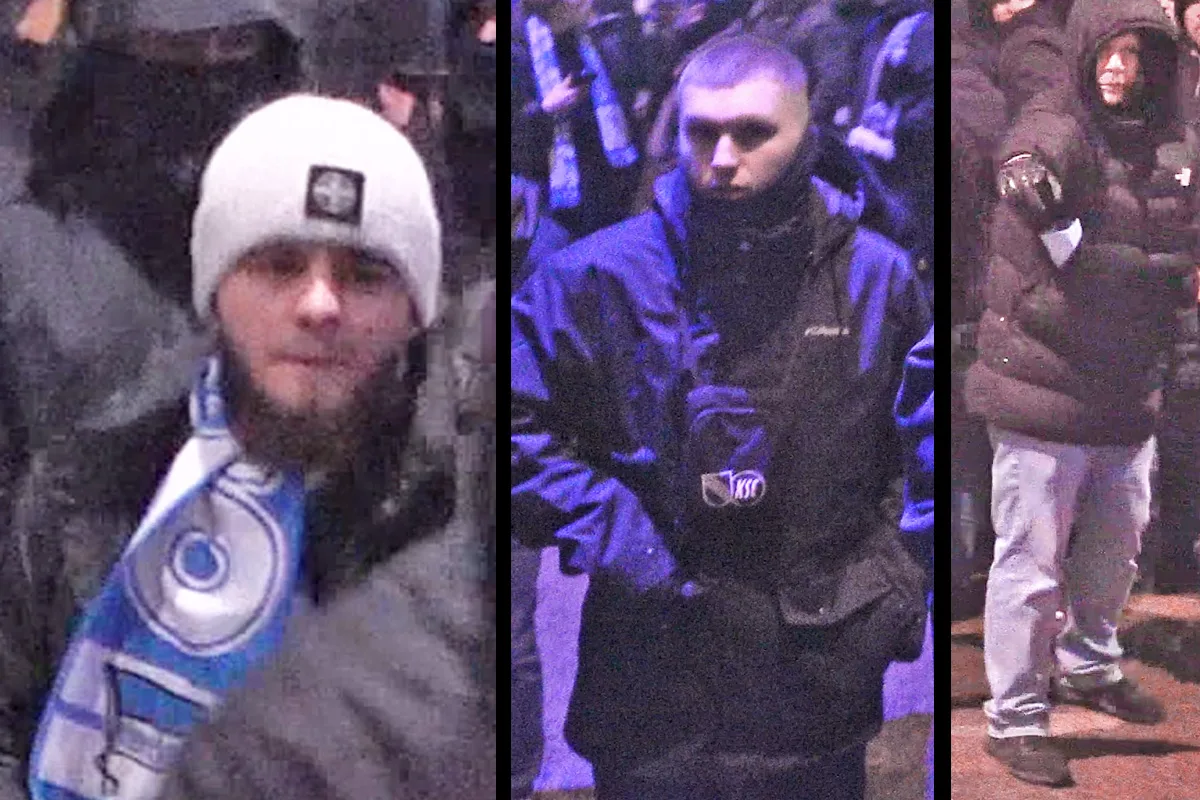 Drei Männer in Menschenmenge, einer trägt eine weiße Mütze, der zweite eine dunkle Jacke und der dritte zeigt mit dem Finger.
