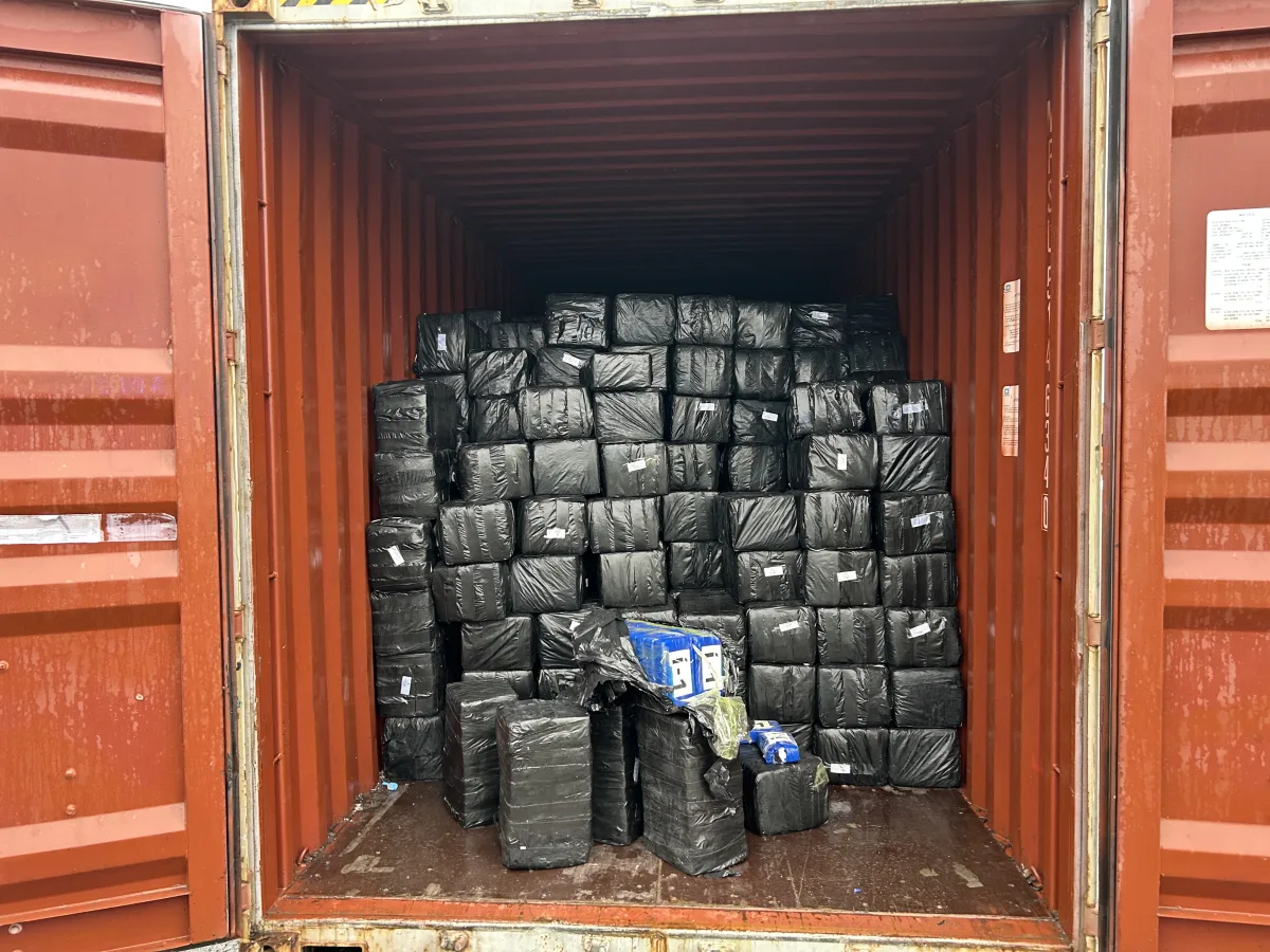 Ein roter Container ist geöffnet und mit vielen schwarzen Paketen gefüllt. Die Pakete scheinen gleichmäßig gestapelt zu sein.