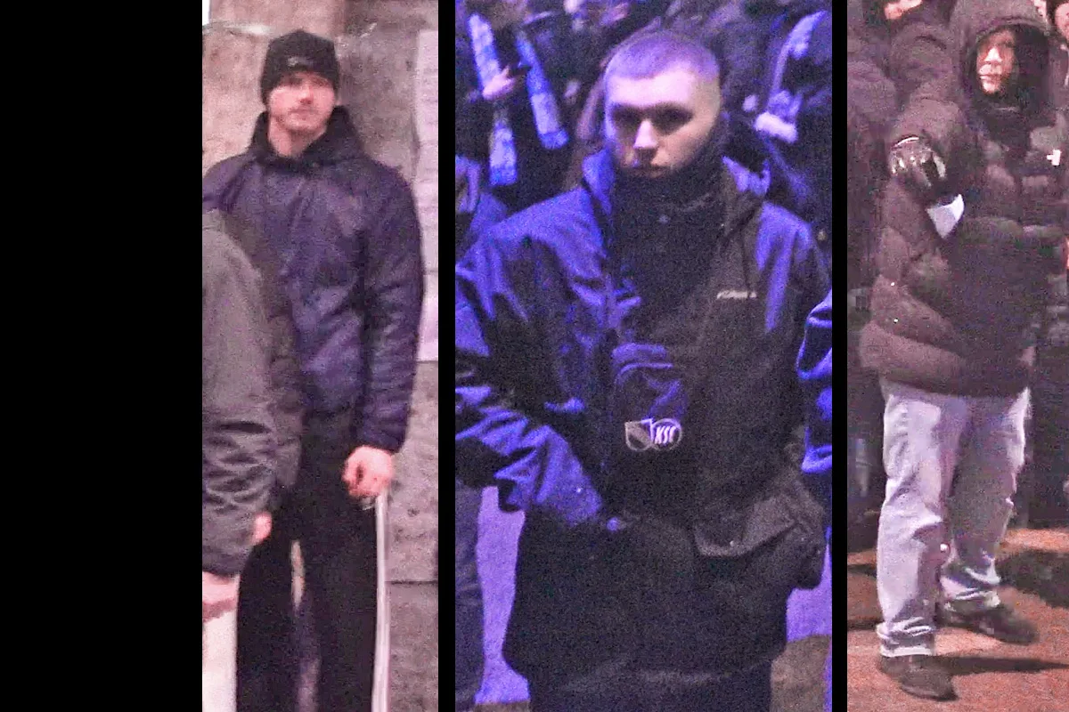 Drei Personen tragen dunkle Kleidung bei Nacht. Sie blicken in unterschiedlicher Richtung und stehen auf einer belebten Straße.