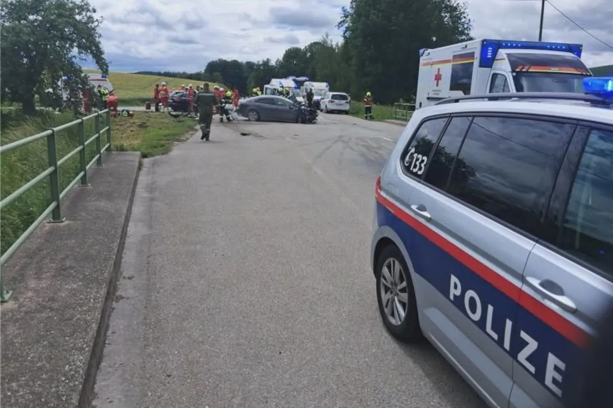 Ein Polizei- und Rettungsfahrzeug stehen nahe eines Unfallortes auf einer Landstraße. Einsatzkräfte sind vor Ort aktiv.
