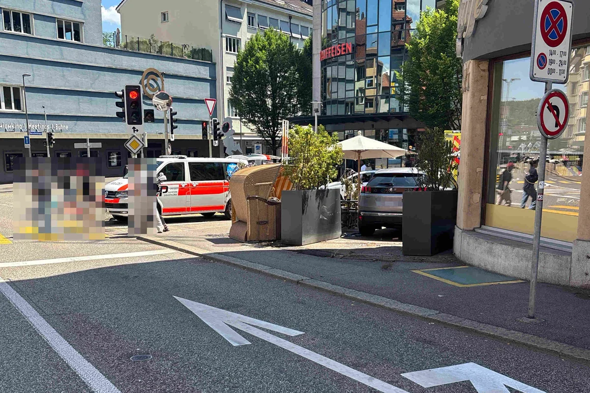 Ein Polizeifahrzeug steht bei einer Kreuzung vor einem Gebäude in der Stadt. Im Hintergrund sind Verkehrszeichen und Infrastruktur zu sehen.