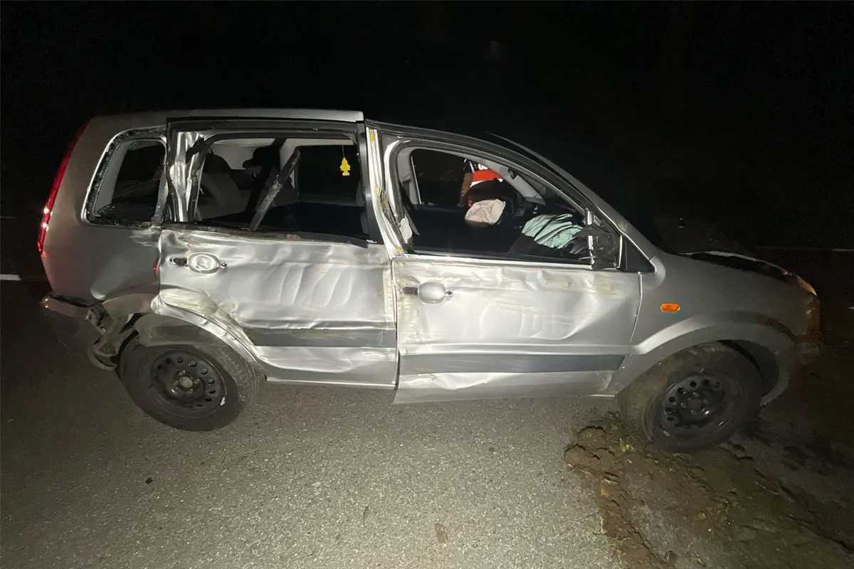 Ein silbernes Auto mit stark verformter Seitentür steht auf einer Straße in der Dunkelheit. Der Innenraum ist sichtbar.
