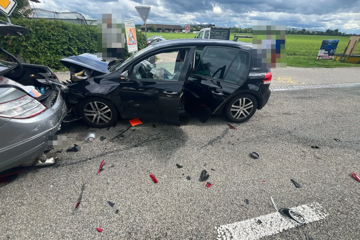 Ein schwarzes Auto ist mit schwerem Frontschaden in das Heck eines silbernen Autos gefahren. Der Unfall fand auf einer Landstraße bei bewölktem Wetter statt.