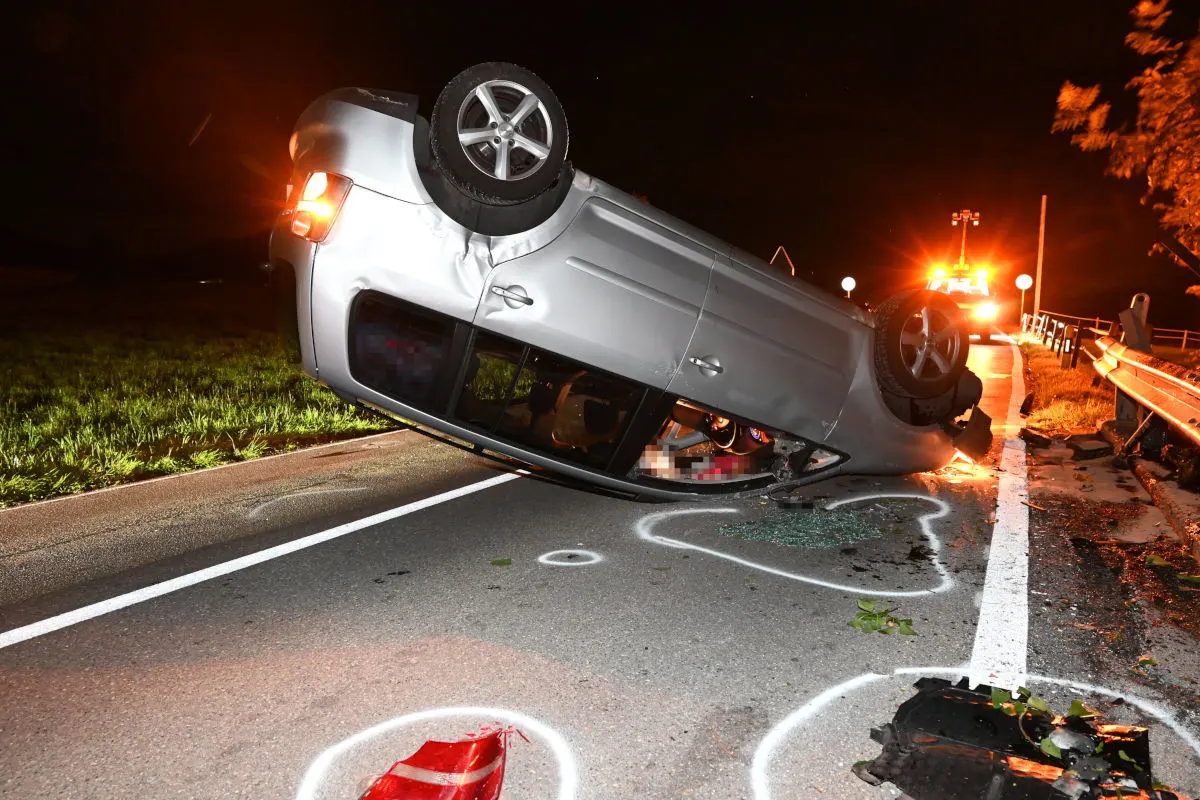 Ein silbernes Auto liegt nach einem Unfall auf dem Dach einer Straße. Um das Fahrzeug herum sind Glasscherben sichtbar.