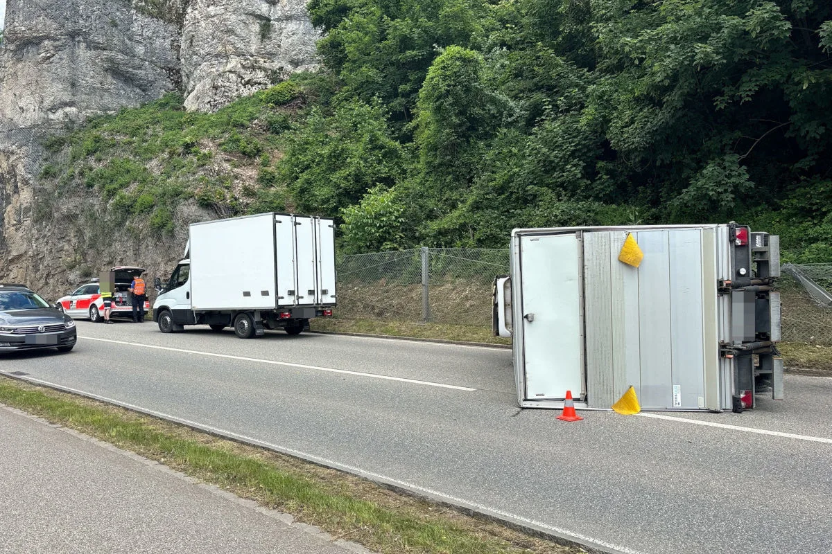 Ein kleiner Lkw liegt auf der Seite auf einer zweispurigen Landstraße. Ein weiteres Fahrzeug steht in der Nähe.
