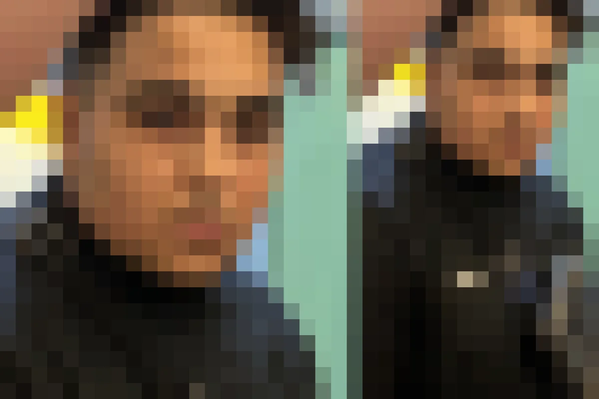 Das Bild zeigt eine nahaufnahme einer Person in schwarzer Kleidung mit einer Tasche im Vordergrund. Dahinter ist ein verschwommener Hintergrund zu sehen.