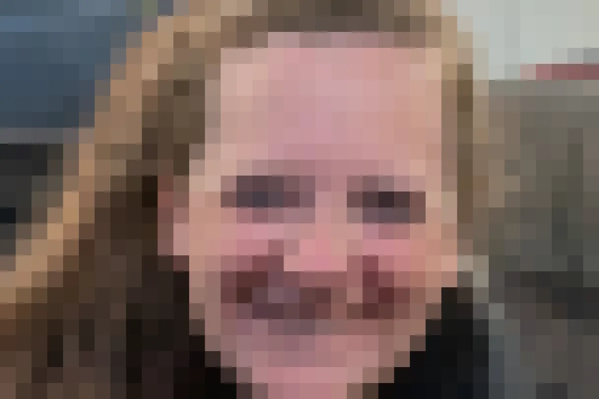 Die Frau mit langen Haaren lächelt in die Kamera, im Hintergrund sind Zugfenster und Sitze auszumachen.