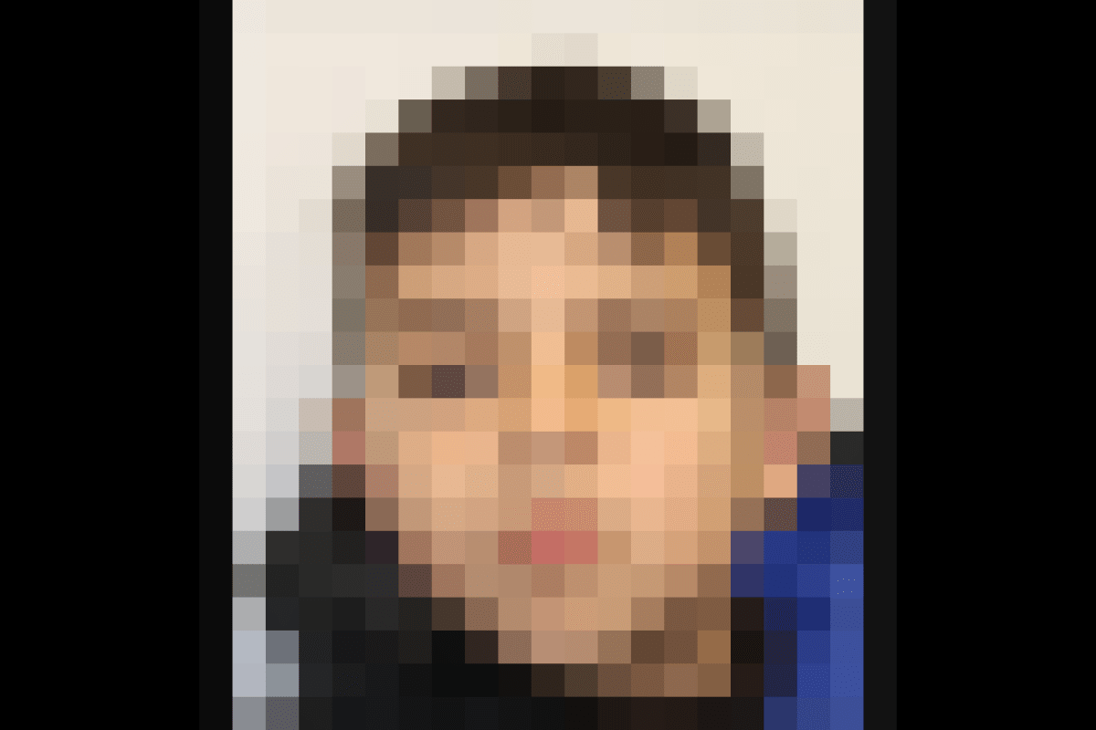 Ein Porträt zeigt einen jungen Jungen mit dunklen Haaren und ernstem Blick vor einer weißen Wand. Der Junge trägt eine schwarze Jacke mit blauen Akzenten.