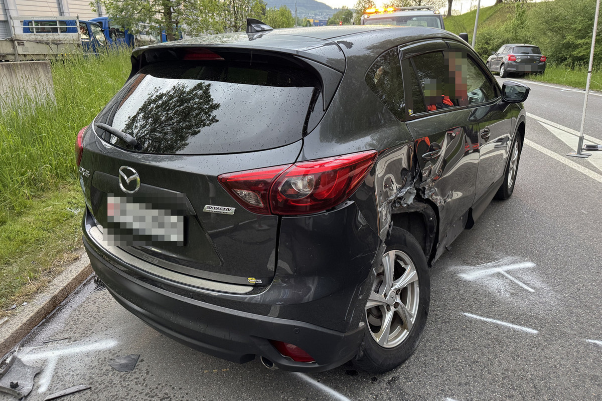 Das Bild zeigt ein graues Auto mit sichtbaren Dellen und Kratzern auf der rechten Seite. Es ist auf einer Straße geparkt, und im Hintergrund sind andere Fahrzeuge sichtbar.