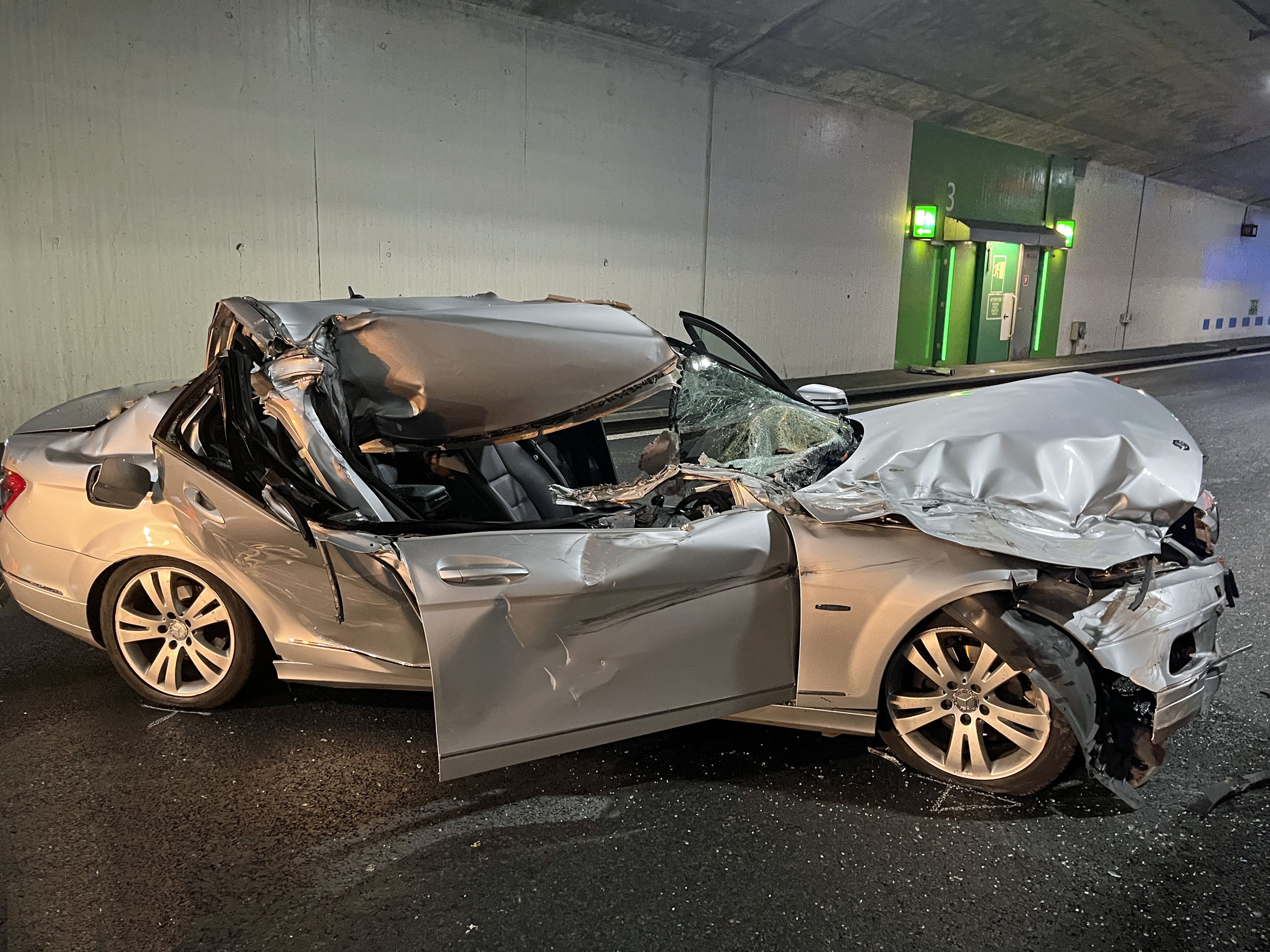 Beschädigtes silbernes Auto in einem Tunnel.