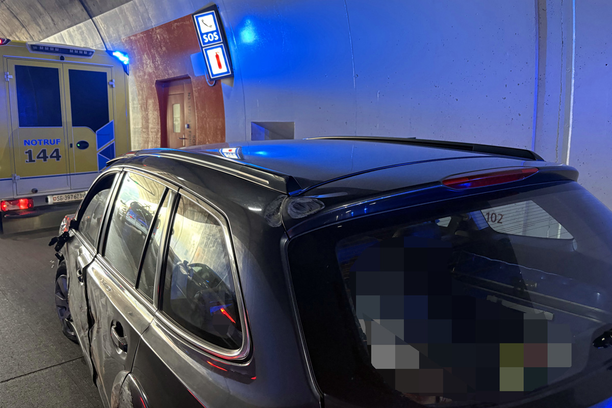 Beschädigtes Auto und Rettungswagen in einem Tunnel.