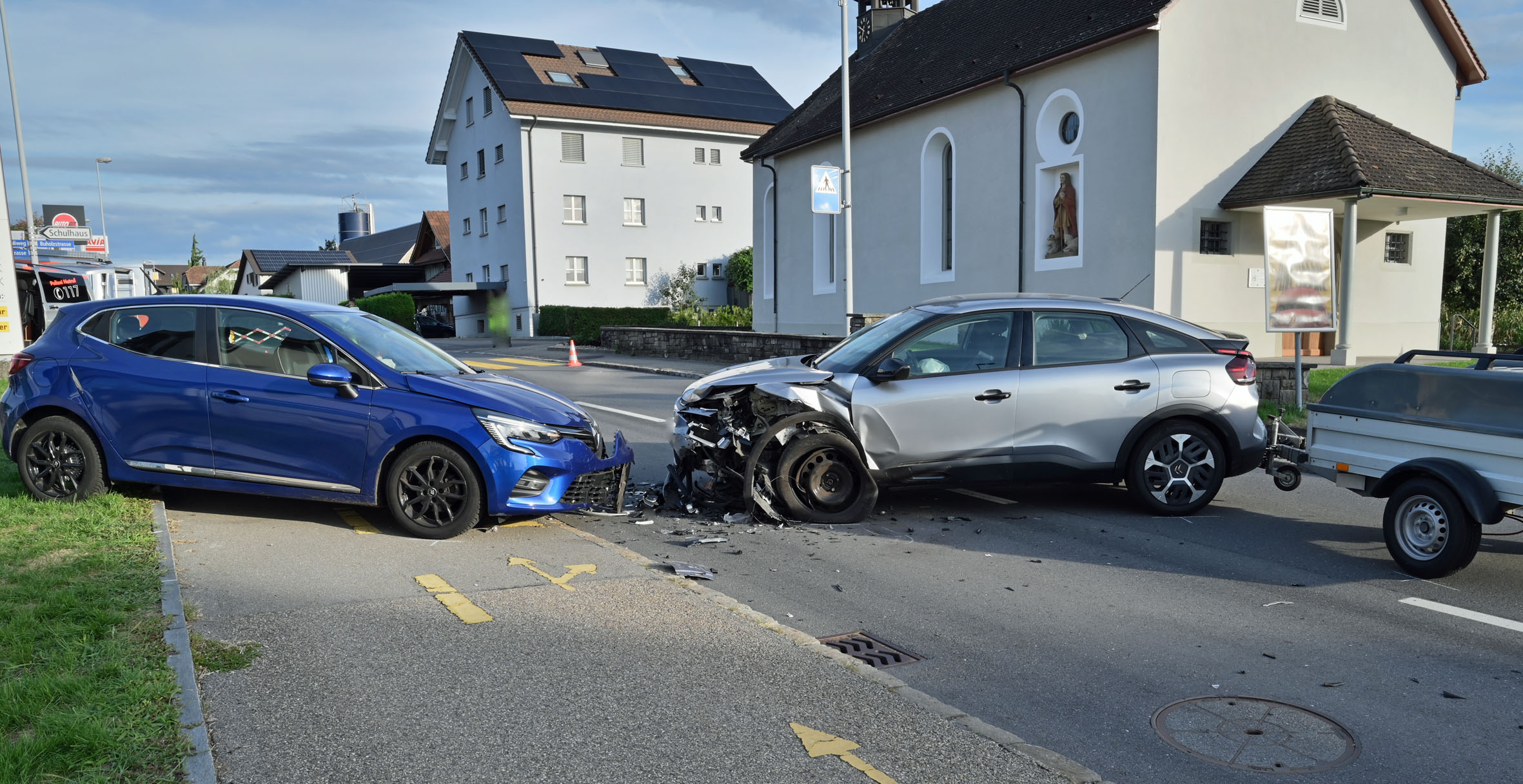 Frontalzusammenstoß zwischen silbernem und blauem Auto an Straßenkreuzung.
