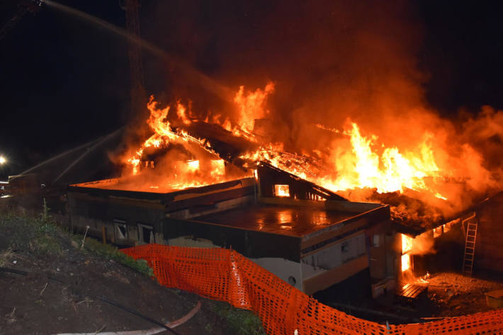 Das Bergrestaurant Foppa steht in Vollbrand. Feuerwehrleute spritzen aus drei Richtungen Wasser in die Flammen.