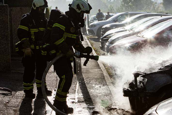Die Einsatzkräfte löschen das brennende Fahrzeug.