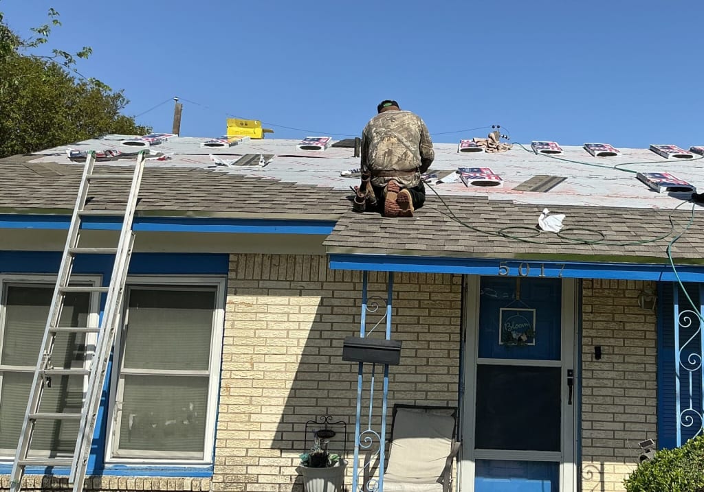 A person working on a roof with a ladder nearby, applying materials in clear weather.