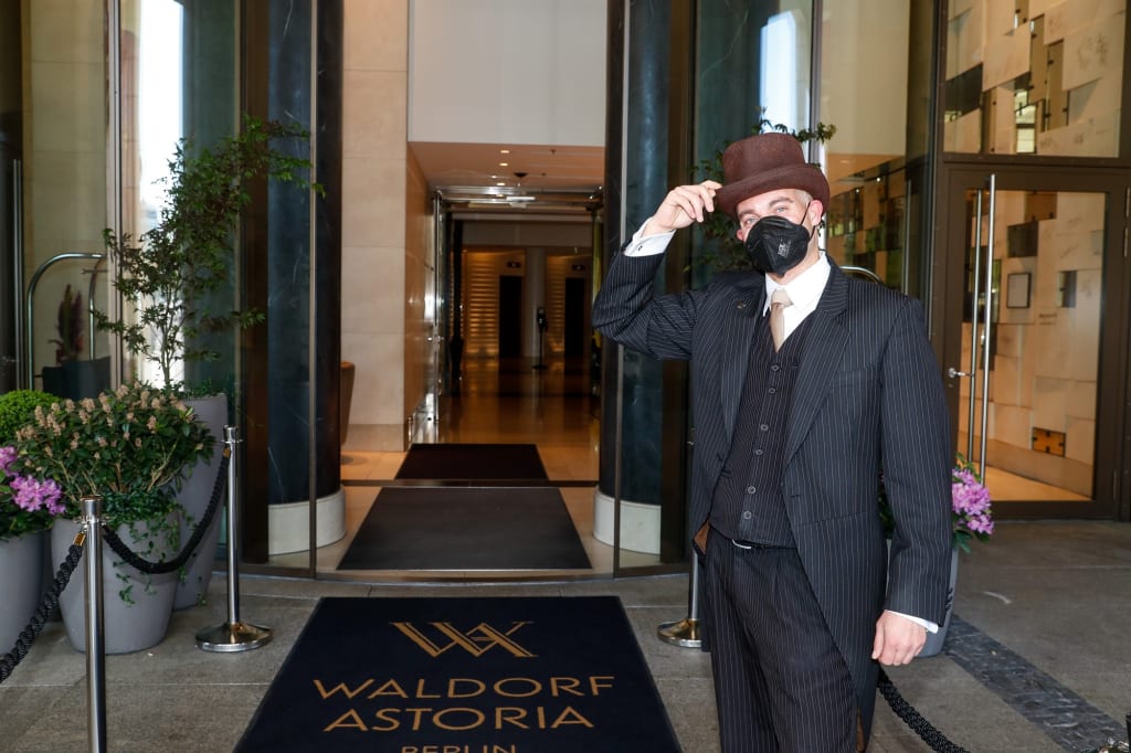 Ein Portier im Waldorf Astoria Berlin bereitet sich darauf vor, Freizeitgäste zu begrüßen, während die Hotels in der Hauptstadt wieder für Touristen öffnen. Die Suchanfragen für die Hilton Hotels in Berlin sind im Vergleich zum Vormonat um 48 Prozent gestiegen, da Reisende wieder Wochenendtrips in die Stadt buchen möchten. Im Laufe des nächsten Monats wird das Team des Luxushotels im Stadtzentrum rund 5.000 Handtücher waschen, 2.100 Frühstücke servieren, 2.000 Bademäntel bügeln und sich darauf vorbereiten, 150 Champagnerkorken knallen zu lassen, wenn die Urlaubszeit wieder beginnt. / Weiterer Text über ots und www.presseportal.de/nr/131988 / Die Verwendung dieses Bildes ist für redaktionelle Zwecke unter Beachtung ggf. genannter Nutzungsbedingungen honorarfrei. Veröffentlichung bitte mit Bildrechte-Hinweis.