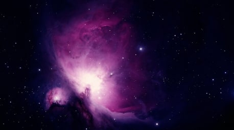 Bild des Orion Nebels, eine weiße Lichtquelle leicht links in der Mittel umgeben von einem lilafarbenen Nebel vor schwarzem Weltall gepunktete mit weißen Sternen