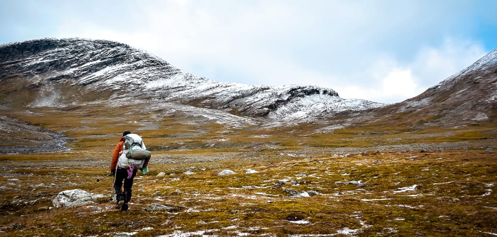 Sabrina Bechtold läuft mit einem großen Rucksack in einer kargen, weiten Landschaft