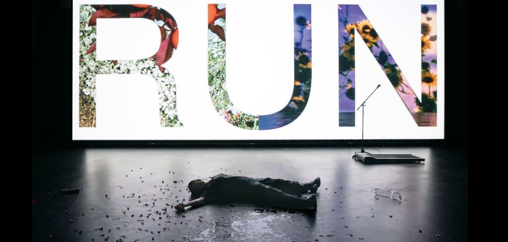 Eine Frau liegt auf dem Boden, an der Wand hinter ihr steht "Run"