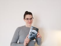 Franziska Morgenstern vor einer hellen Wand mit der Taschenbuchausgabe von Heinrich Manns Roman »Der Untertan«