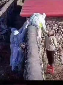 Ein Bürger wird über eine Mauer per Rachenabstrich getestet von drei Männern in Schutzanzügen