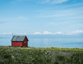 Foto eines roten Schwedenhauses vor Meer