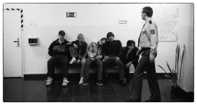 Filmszene aus Als wir träumten bei der Polizei mit Jugendlichen auf einer Bank