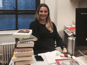 Frau vor Bücherstapel auf dem Schreibtisch