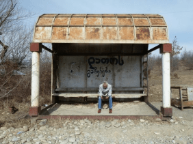 Stephan Wackwitz an einer Bushaltestelle sitzend