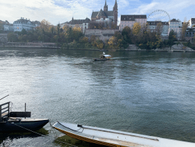 Der Rhein in Basel. Das Bild zeigt einen Ausschnitt des Rheins. Im Hintergrund ist ein Stück Basels abgebildet.