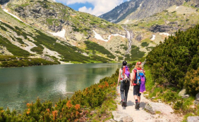 Zwei Personen wandern entlang eines Sees in den Bergen
