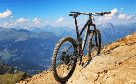 Bike an einem Hang in den Bergen. Im Hintergrund blauer Himmel und Bergkette.