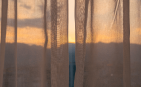 Relativ durchsichtige Vorhänge zeigen einen warmen Sonnenaufgang