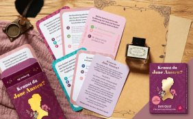 Ausgebreitete Quizkarten aus dem Kartenspiel "Kennst du Jane Austen?" mit einer Tintenflasche, einer Feder und der Quiz-Verpackung.