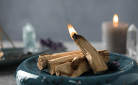 Schale mit Räucherhölzern, im Hintergrund Kerzen und Kristalle