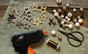 Materialien für das DIY wie z.B. Schere, verschiedene Holzperlen, Draht, Heißkleber, Sterne 
