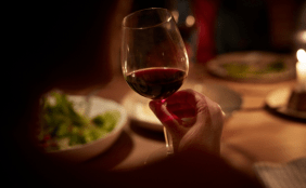 Weinglas mit Rotwein und gedeckter Tisch in gemütlicher Atmosphäre