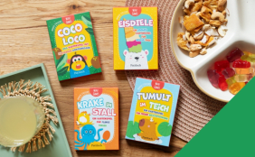 4 Mini-Games abgebildet auf einem Tisch mit kleinen Snacks. Vordergrund rechts untere Ecke: ein grünes Dreieck