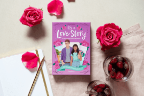 Das Kartenset "It's a Love Story" au einem Tisch, drumherum Rosenköpfe, Notizbuch mit Stift und ein Glas mit einem Erdbeergetränk