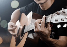 Mann in einem schwarzen T-Shirt, der eine Akustikgitarre spielt