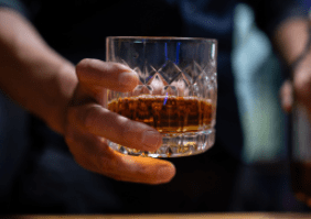 Eine Männerhand, die einen Whiskytumbler hält
