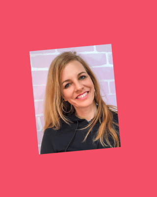 Leo Lührs lächelt in die Kamera, sie steht vor einer rosafarbenen Backsteinwand