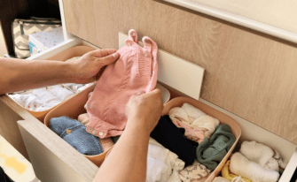 Babykleidung wird in eine Wickelkommode einsortiert
