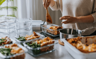 Mans sieht in der rechten Bildhälfte eine Frau im Anschnitt, die Meal-Prep betreibt